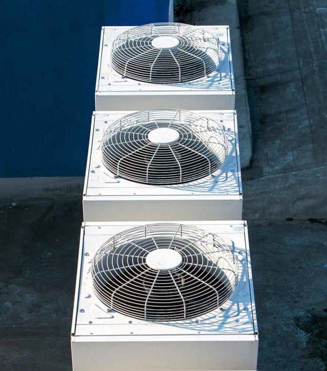 Three air conditioners are sitting on top of a concrete platform.